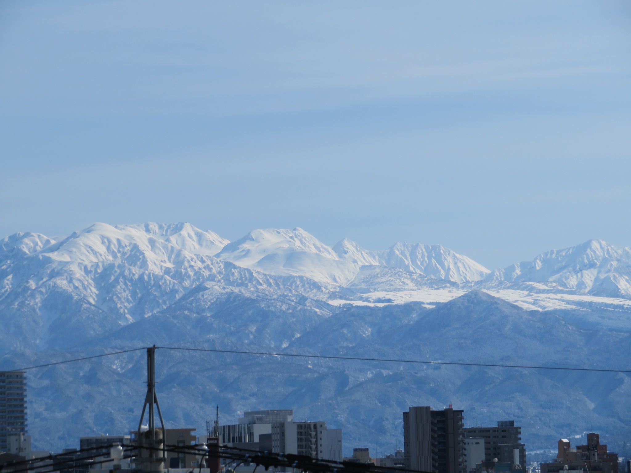 富山平野から望む立山連峰。雪が平らになって見えるところが弥陀ヶ原で、画面左側が「立山」です