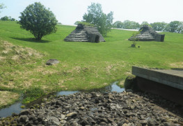 水場の祭祀場の遺構（手前）と復元された竪穴住居