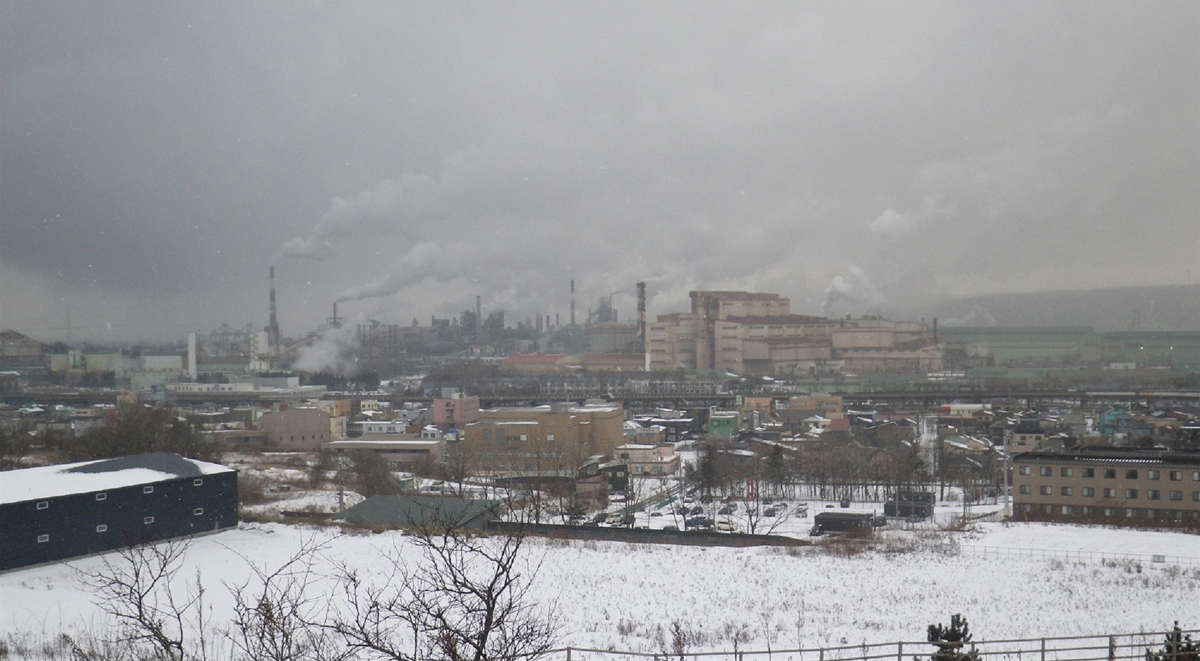 雪が舞う輪西の街並み。後方に見えるのが日本製鉄の工場群（市内の潮見公園展望台より撮影）