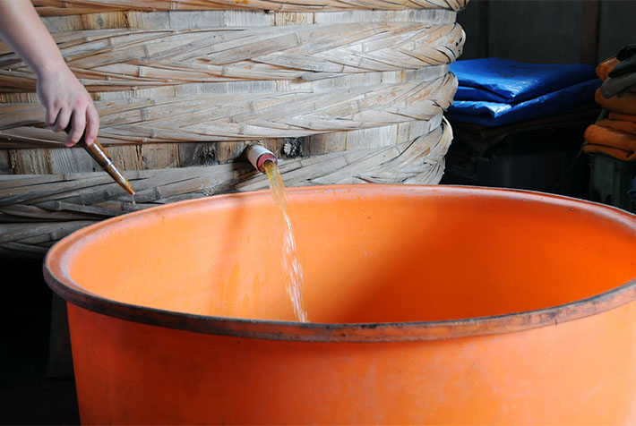 桶から取り出される白醤油が琥珀色に輝く ヤマシン醸造（株）様提供による
