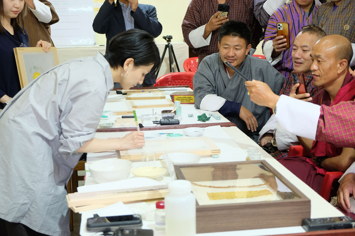 ブータンでのワークショップの様子。岩絵具による絵絹への彩色のデモンストレーション 写真提供:DACC