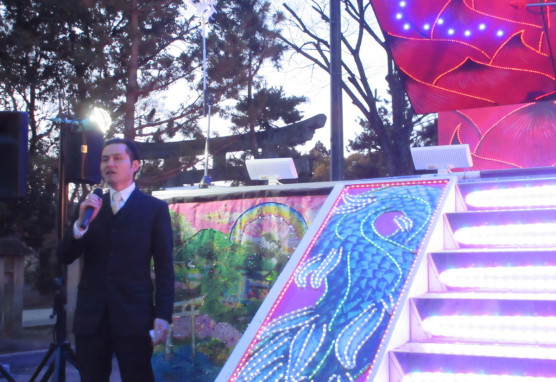 現代京都藝苑2015「悲とアニマ」展で企画者挨拶をする秋丸知貴さん
（2015年３月11日北野天満宮、やなぎみわ《花鳥虹》の前で）