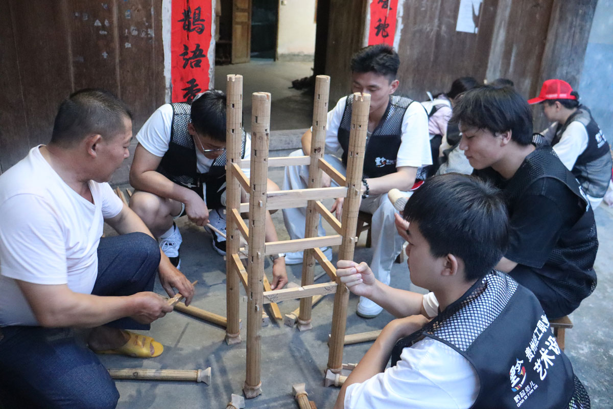 鼓楼の伝承者から指導を受け、四季を象徴する４本の主柱の建て方を学ぶ調査チームの様子