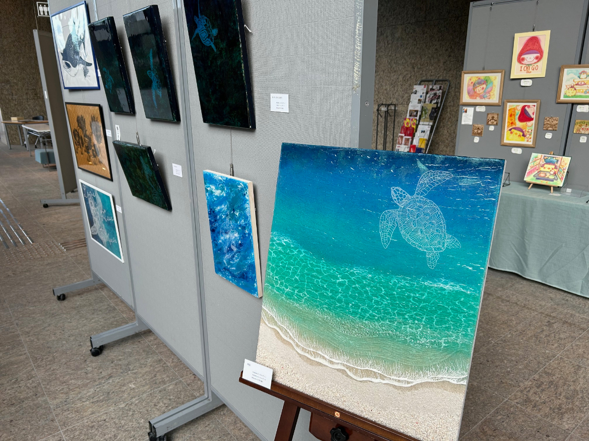 山口さんの切り絵が、沖縄の「美ら海」アートの第一人者であるtsubomi氏と、BRIWOOD・HIKARU氏の手による美しい海を泳ぐ