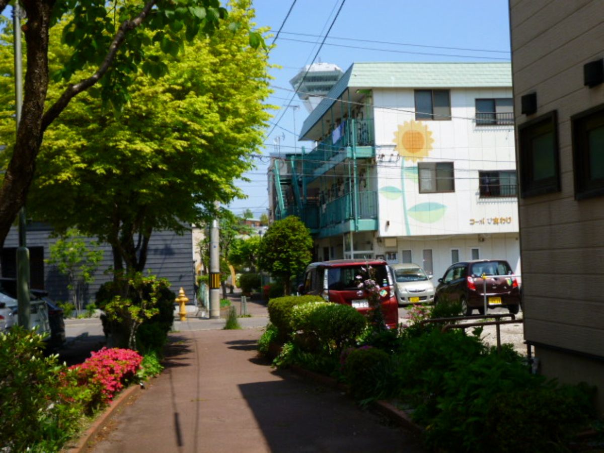 進んでいく。壁面に描かれた黄色のひまわりの花と屋根と階段の緑色が木々に溶け込んでいる